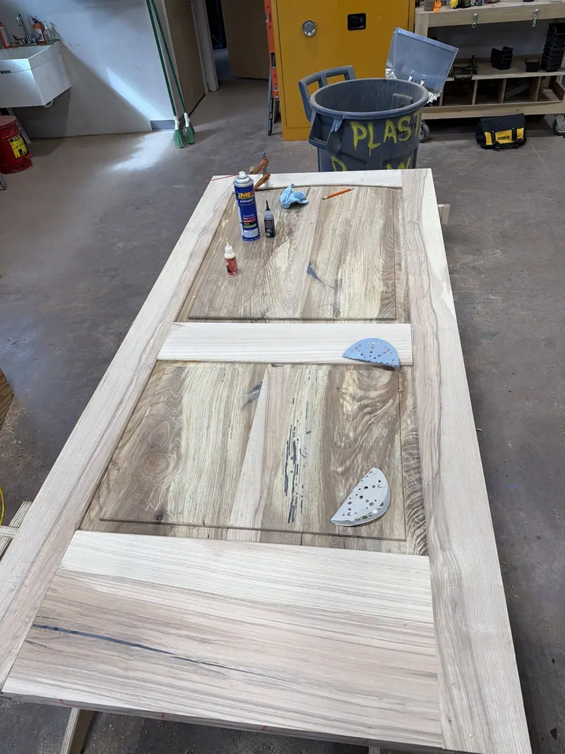 Wood door on a workshop bench during surface preparation.
