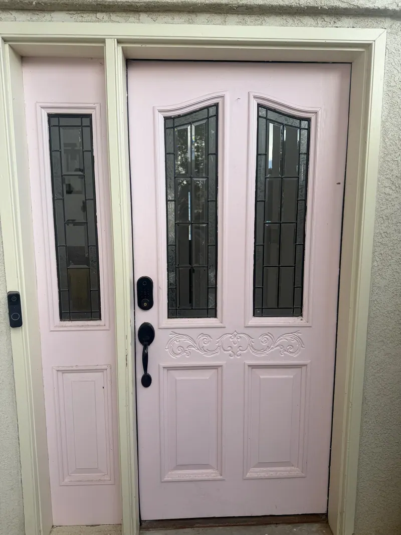 Light pink entry door with decorative glass.